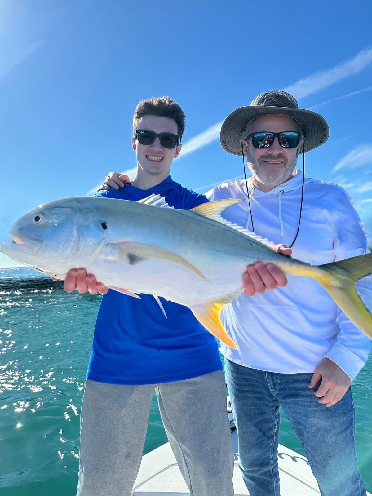 Two anglers holding a big jack crevalle on the boat