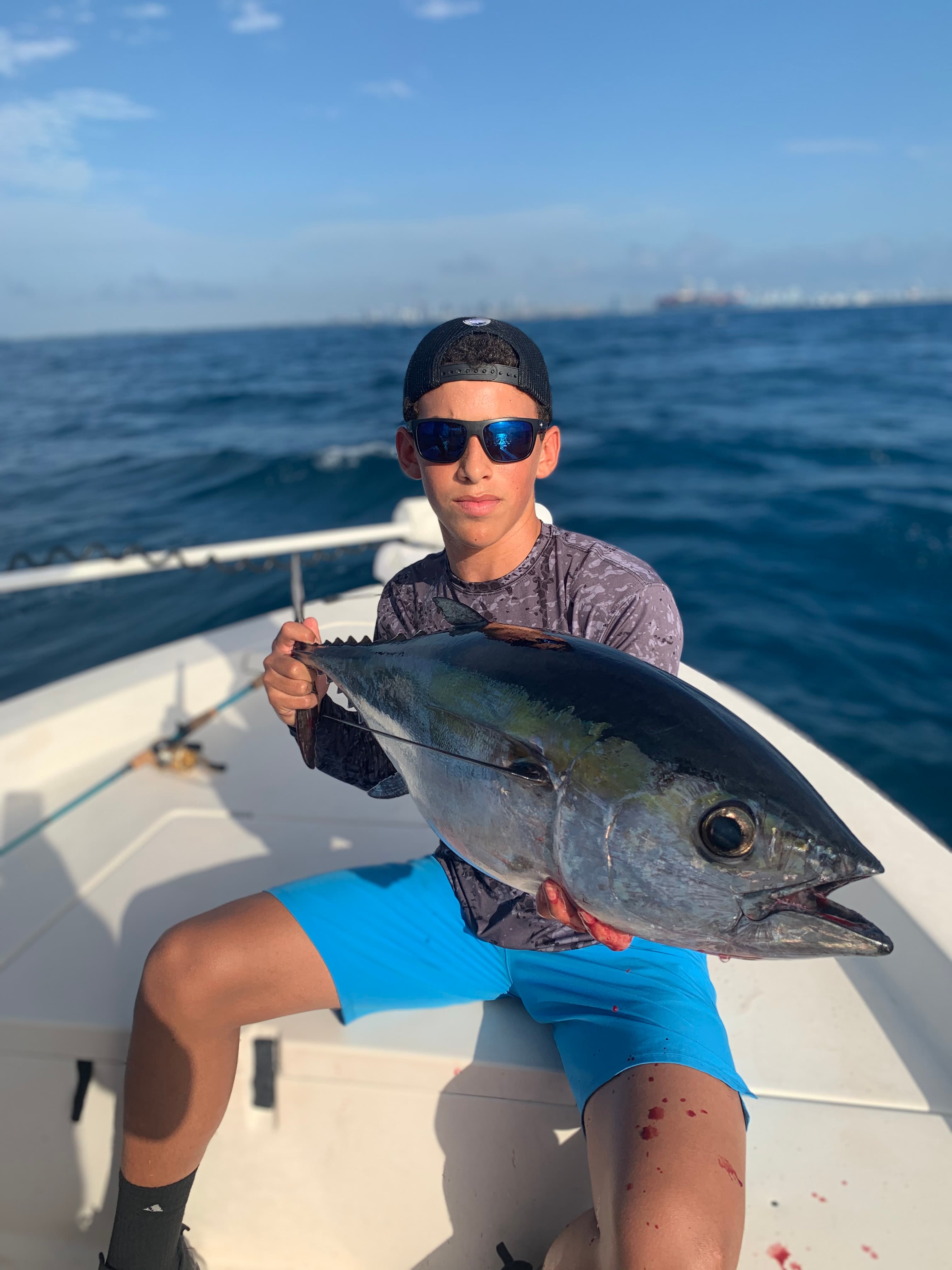 Young angler on the bow holding a blackfin tuna