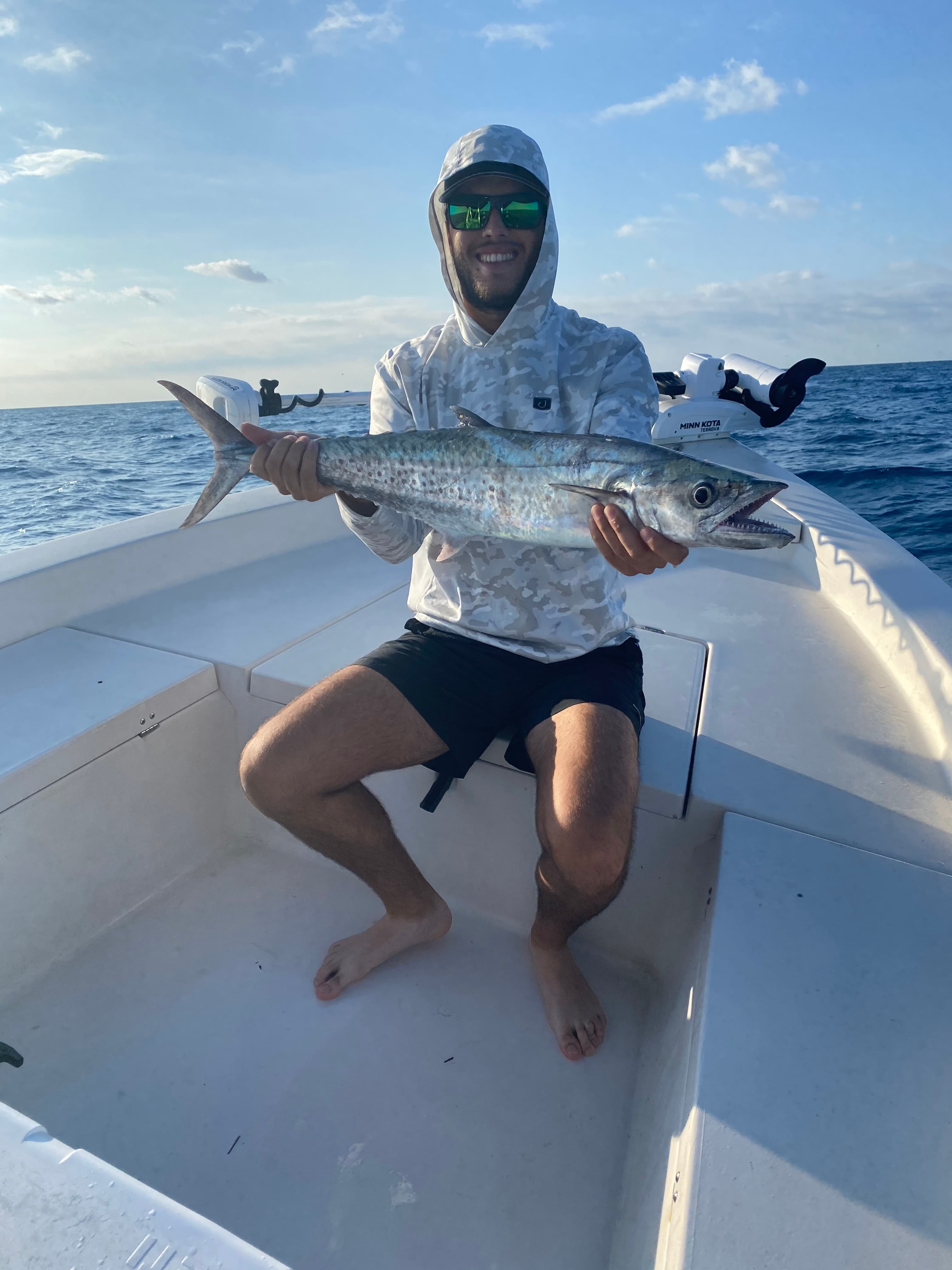 Angler with a kingfish at the bow beside the Minn Kota trolling motor
